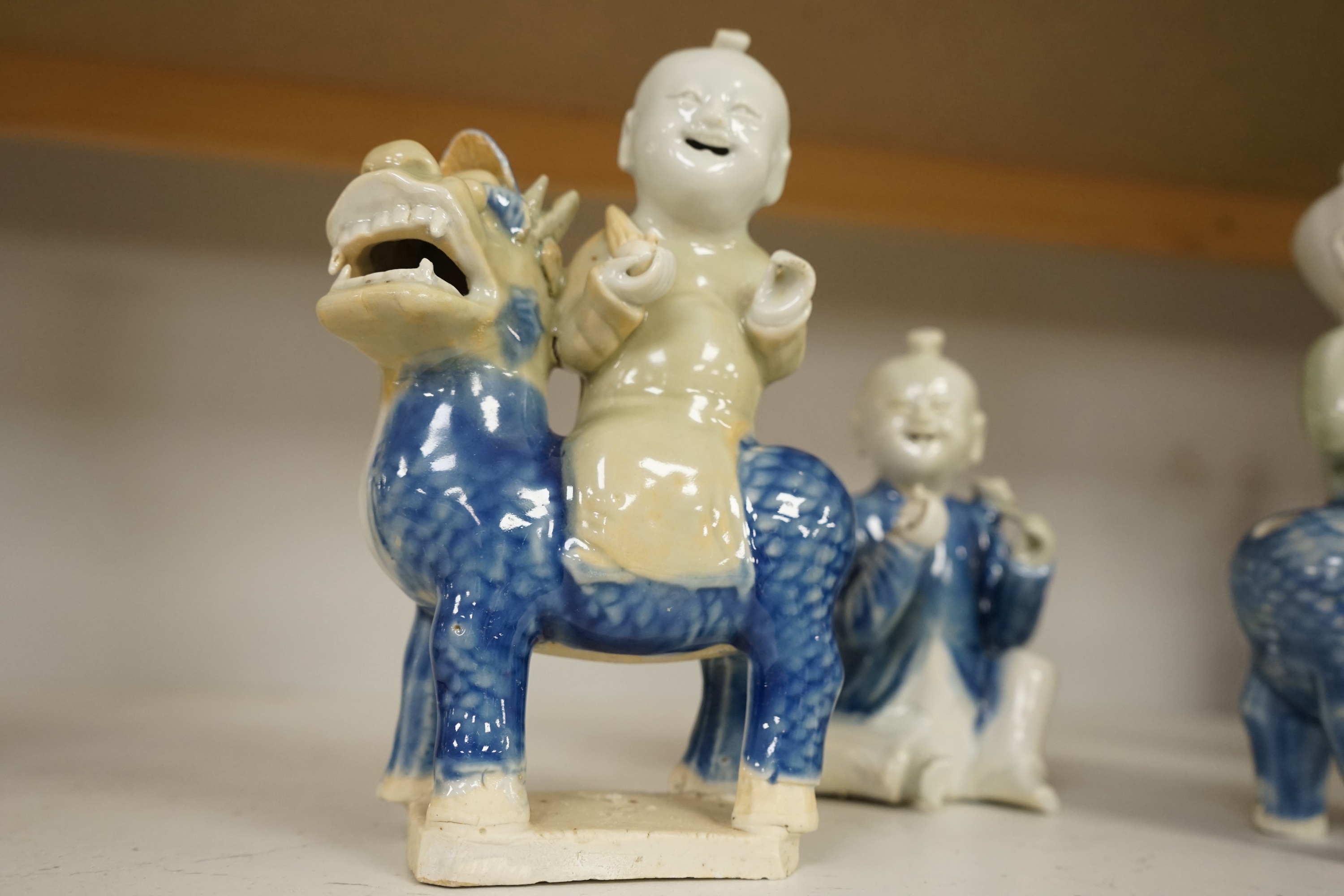 Three Chinese celadon and blue glazed porcelain boy figures, 18th century, largest 20cm high. Condition - fair, all restored